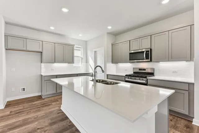 a kitchen with stainless steel appliances granite countertop a sink a stove and a refrigerator