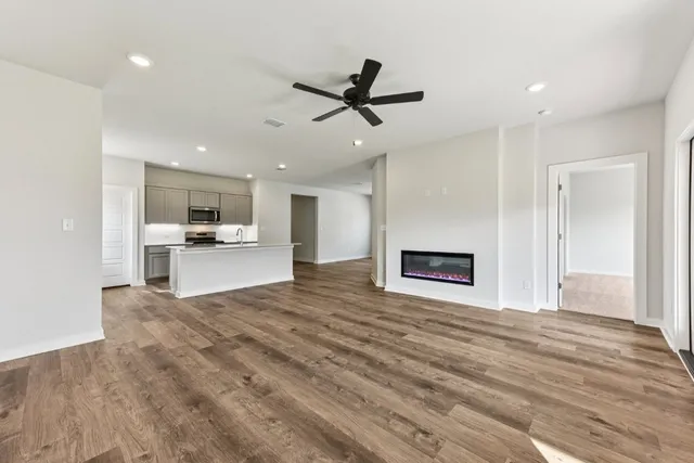 a view of an empty room with kitchen and a window