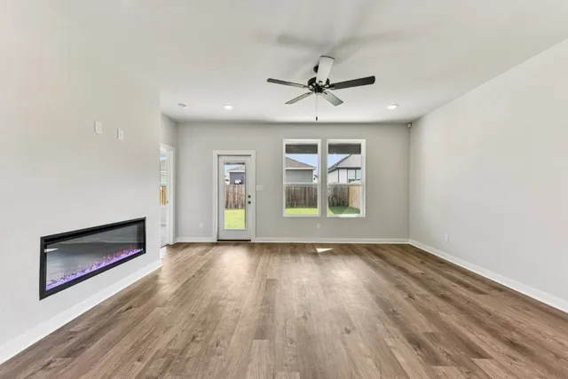 an empty room with wooden floor a ceiling fan and windows