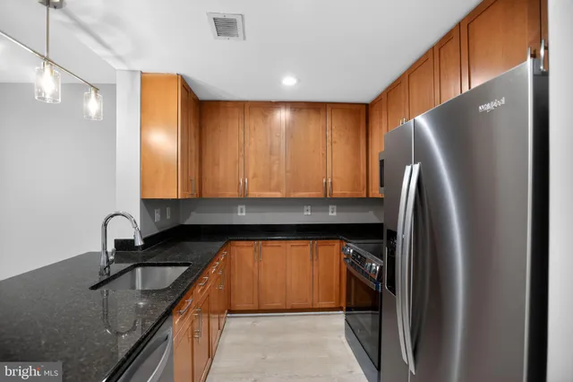 a kitchen with stainless steel appliances granite countertop a sink a stove and refrigerator