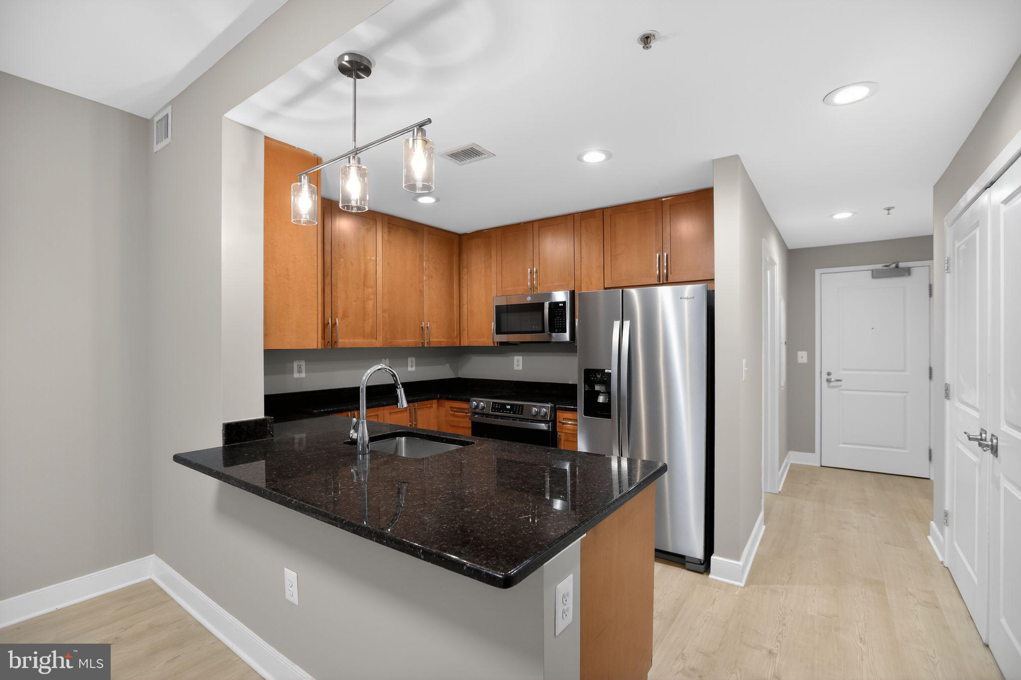 4101 Albemarle Street Northwest, Unit 317 Washington, DC 20016 - Photo 19 of 32 a kitchen with stainless steel appliances granite countertop a sink a stove and refrigerator