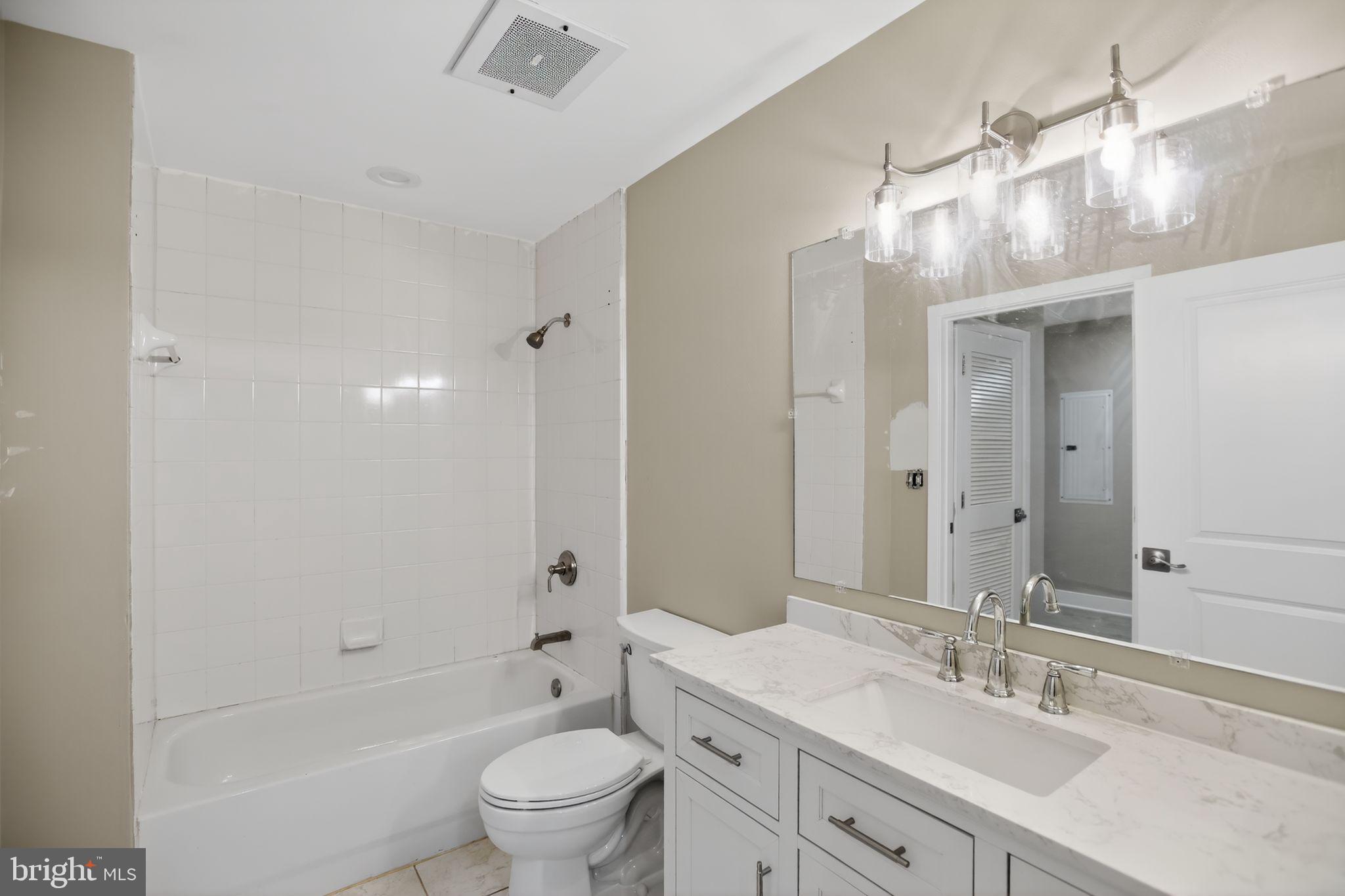 4101 Albemarle Street Northwest, Unit 317 Washington, DC 20016 - Photo 26 of 32 a bathroom with a granite countertop sink a toilet and shower