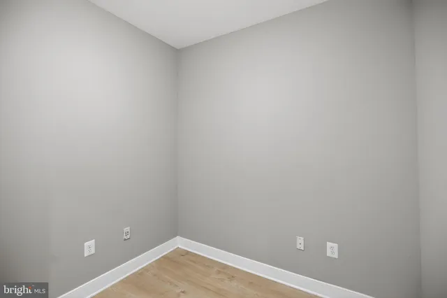 a view of a hallway with wooden floor and a kitchen space