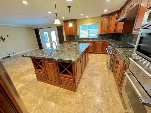 a kitchen with stainless steel appliances granite countertop a sink a stove and a wooden cabinets