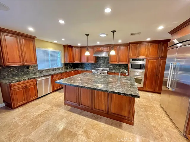 a kitchen with stainless steel appliances granite countertop wooden cabinets a refrigerator and a sink