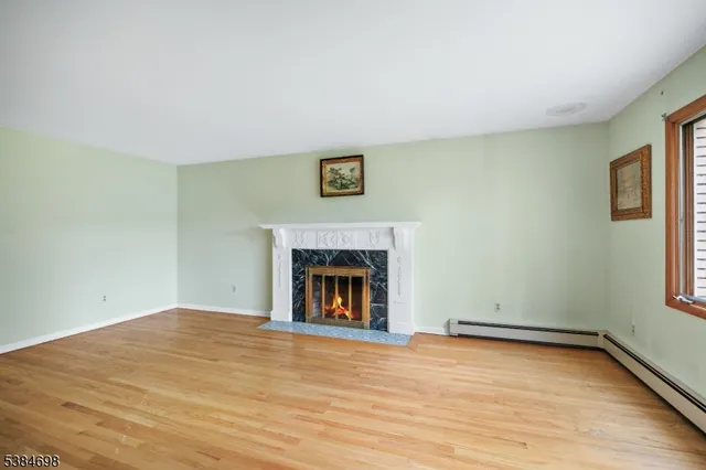 a view of empty room with wooden floor and fireplace