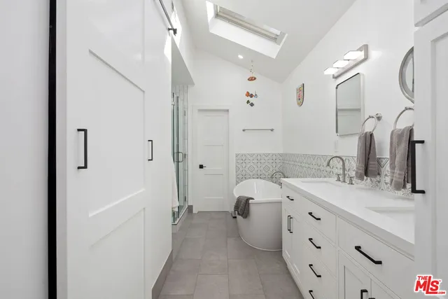 a bathroom with a double vanity sink a mirror and a bathtub