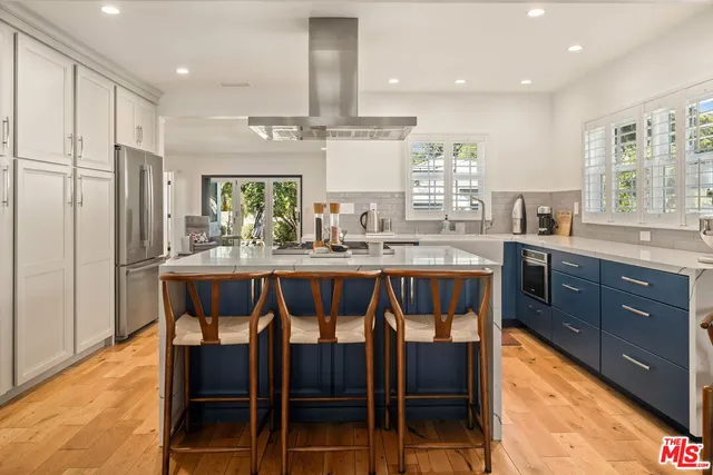 a kitchen with stainless steel appliances kitchen island granite countertop a table chairs sink and cabinets