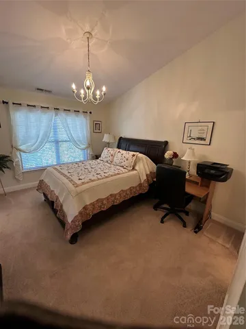 a bedroom with a bed window and a chandelier