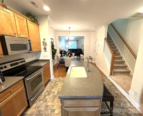a living room with stainless steel appliances furniture a rug and a view of kitchen