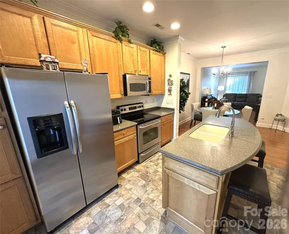 a kitchen with stainless steel appliances granite countertop a refrigerator a stove a sink a dining table and chairs with wooden floor