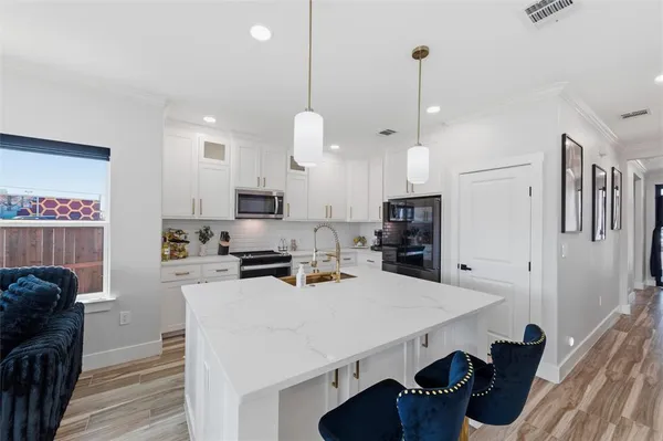 a kitchen with granite countertop a sink a counter top space stainless steel appliances and cabinets