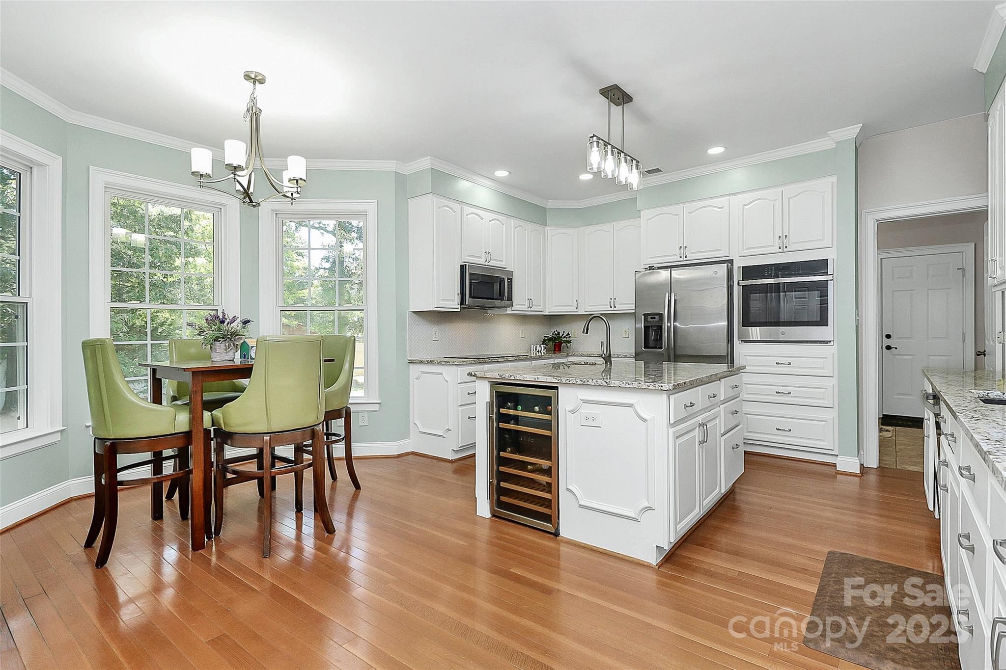 514 Bethel School Road Clover, SC 29710 - Photo 8 of 28 a kitchen with stainless steel appliances granite countertop a stove top oven a refrigerator a kitchen island a dining table and chairs with wooden floor