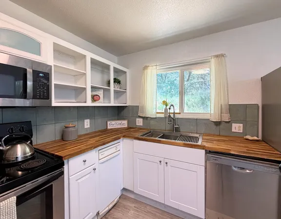 a kitchen with a sink dishwasher window and cabinets