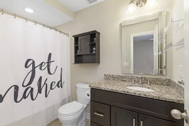 a bathroom with a granite countertop sink a toilet and mirror