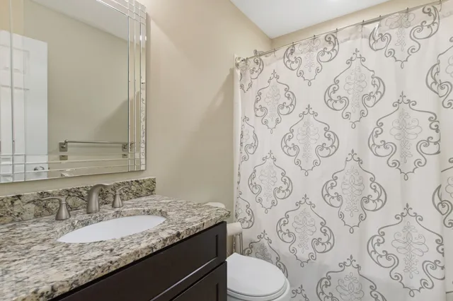 a bathroom with a granite countertop toilet a sink and a mirror