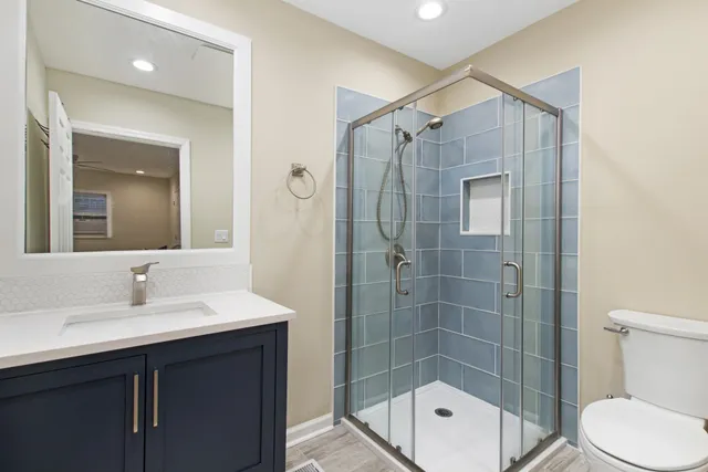 a bathroom with a shower sink vanity mirror and toilet