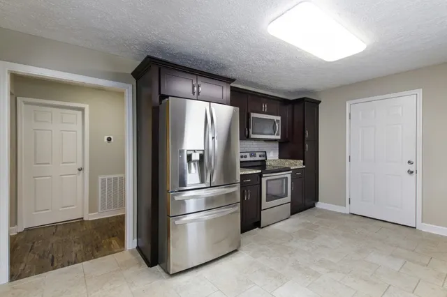 a kitchen with stainless steel appliances granite countertop a refrigerator and a stove
