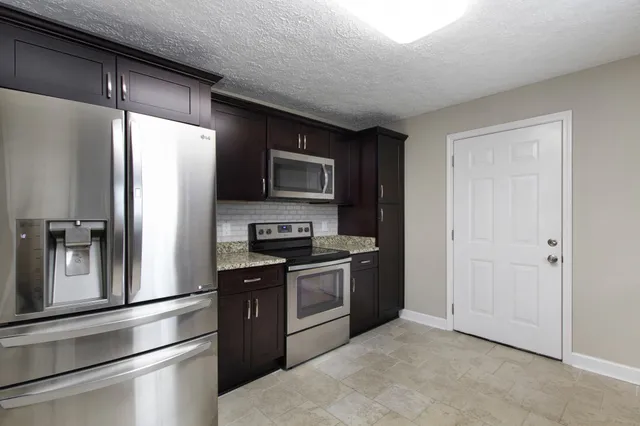 a kitchen with stainless steel appliances granite countertop a refrigerator a stove and a sink