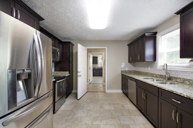 a kitchen with stainless steel appliances granite countertop a refrigerator and a sink