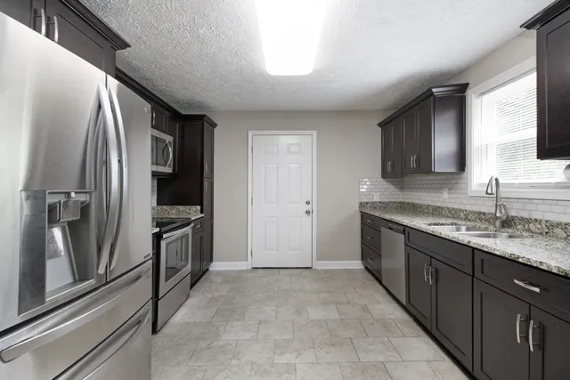 a kitchen with stainless steel appliances granite countertop a refrigerator and a sink