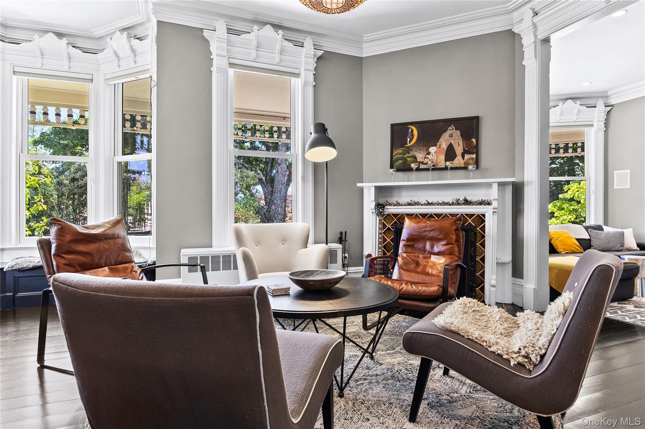 19 Howe Place Bronxville, NY 10708 - Photo 6 of 37 Living area featuring dark wood-finish flooring, a decorative fireplace with patterned tile surround, and a bay window
