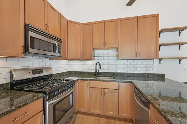 a kitchen with granite countertop cabinets stainless steel appliances and a sink