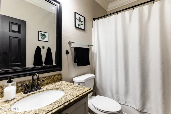 a bathroom with a granite countertop sink mirror vanity and toilet