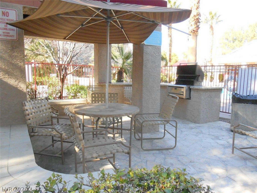 9325 West Desert Inn Road, Unit 132 Las Vegas, NV 89117 - Photo 29 of 36 An inviting outdoor patio features a shaded dining area and a convenient built-in grill.