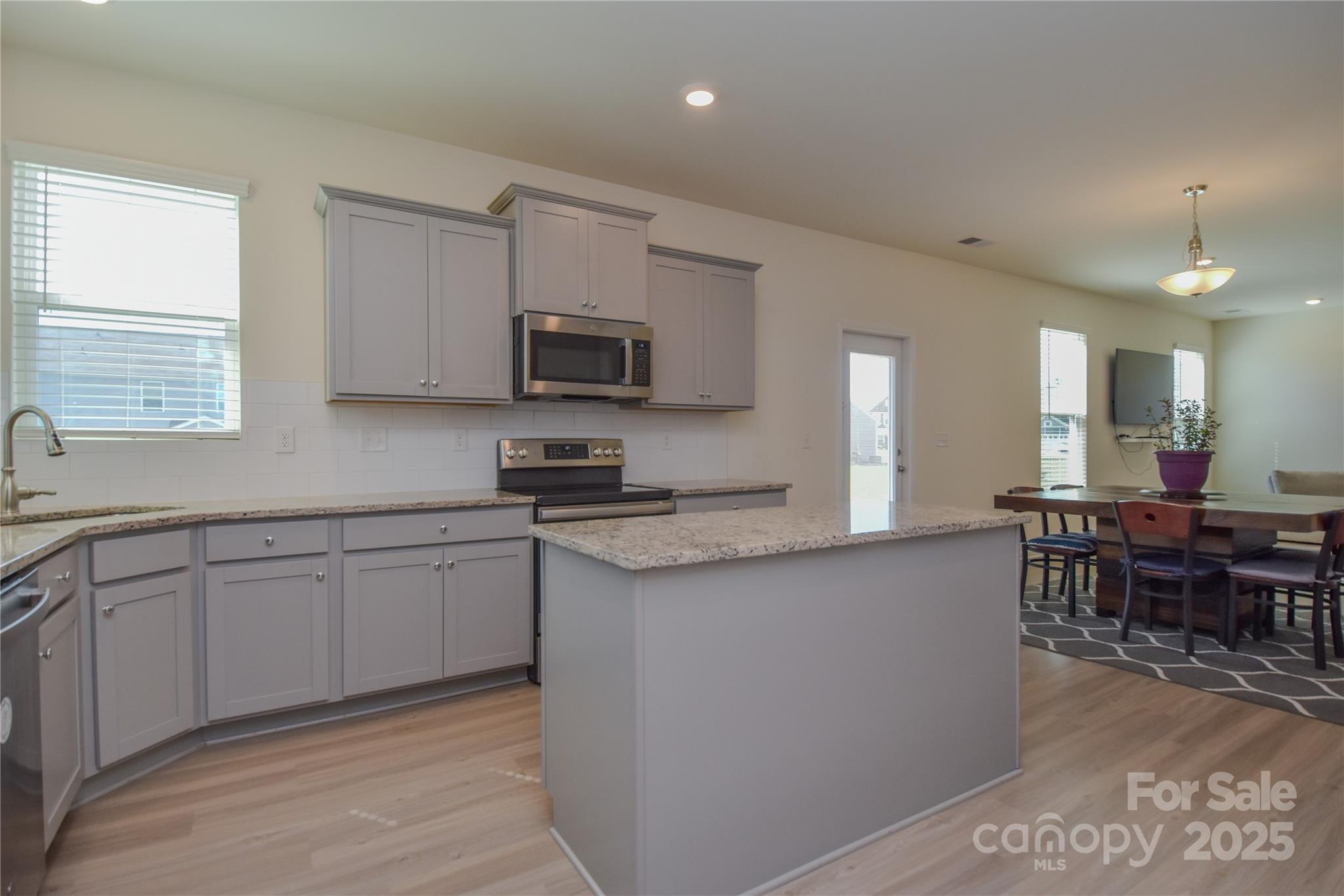 139 West Neel Ranch Road Mooresville, NC 28115 - Photo 8 of 40 a kitchen with stainless steel appliances granite countertop a stove top oven a sink dishwasher a dining table and chairs with wooden floor