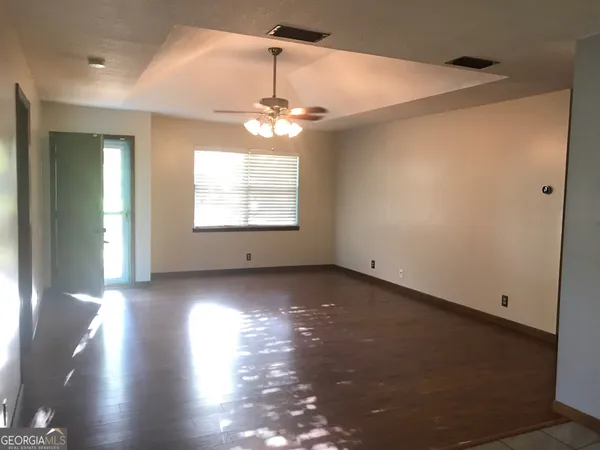 an empty room with wooden floor and windows