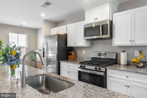 a kitchen with stainless steel appliances granite countertop a sink a stove a microwave and refrigerator