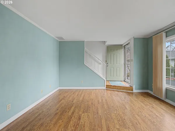 an empty room with wooden floor and windows