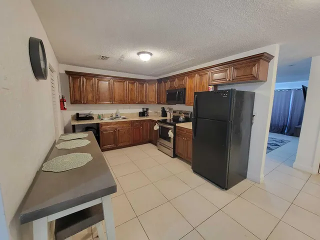 a kitchen with granite countertop a refrigerator and a stove top oven