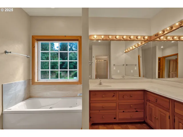 a bathroom with a granite countertop sink a large mirror and a bathtub