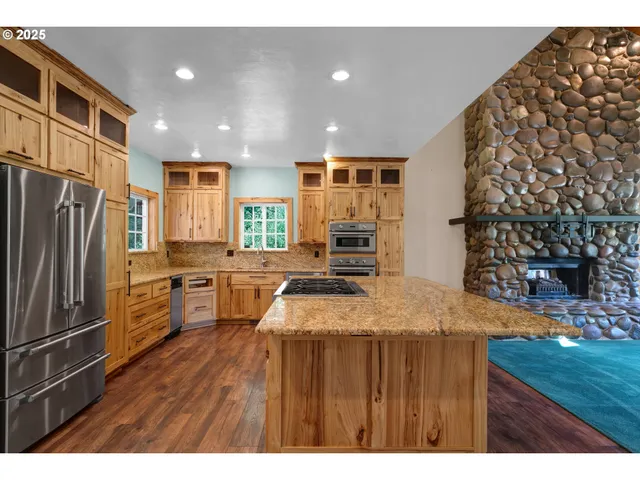 a kitchen with kitchen island a counter top space a sink stainless steel appliances and cabinets