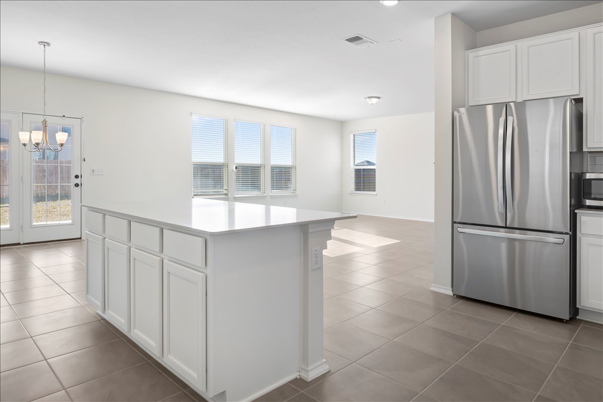 18501 Spotted Eagle Lane Elgin, TX 78621 - Photo 11 of 40 A well-lit kitchen featuring an island with ample storage, sleek stainless steel appliances, and durable tile flooring.