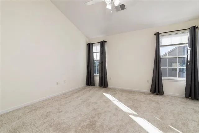 an empty room with a chandelier fan and windows