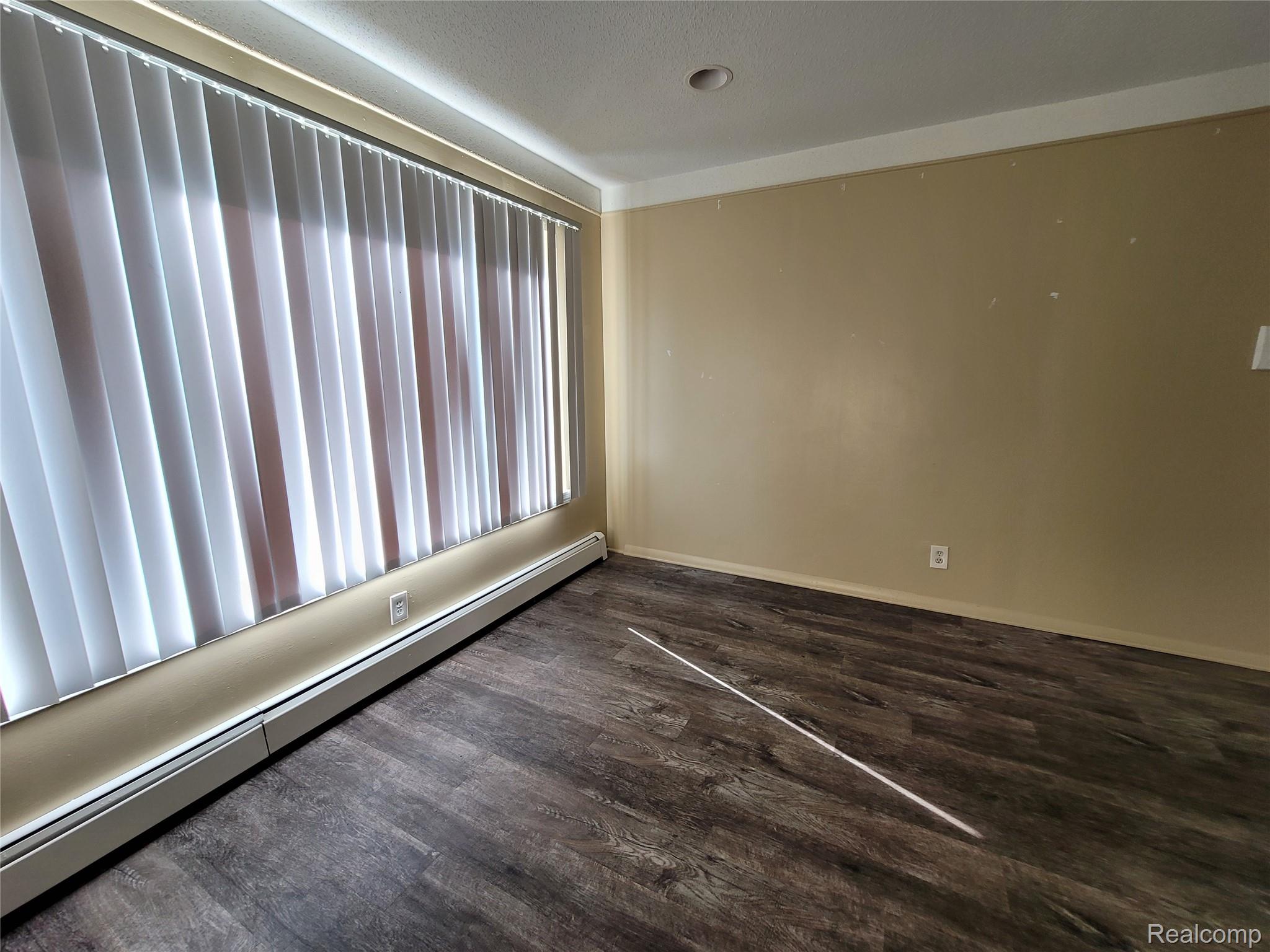 16470 East 9 Mile Road, Unit 104 Eastpointe, MI 48021 - Photo 13 of 14 Spare room with baseboard heating and dark wood-style flooring
