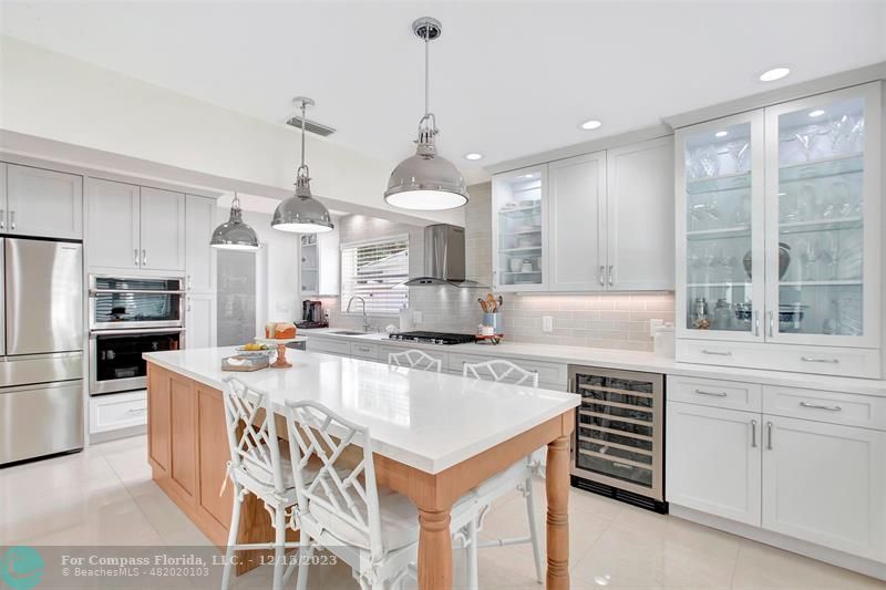 1985 Sailfish Place Pompano Beach, FL 33062 - Photo 16 of 47 a kitchen with kitchen island a stove a table and chairs