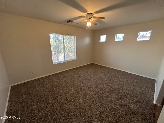 an empty room with windows and fan