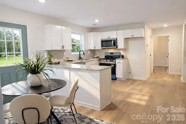 a kitchen with stainless steel appliances kitchen island granite countertop a refrigerator a stove a sink dishwasher a dining table and chairs with wooden floor