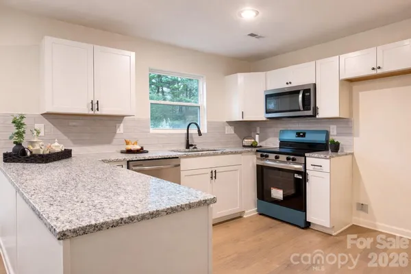 a kitchen with granite countertop a sink stove top oven and microwave