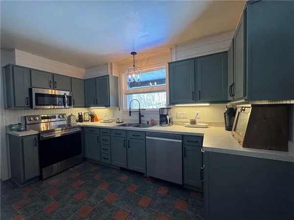 a kitchen with stainless steel appliances granite countertop a sink dishwasher stove and refrigerator with wooden floor