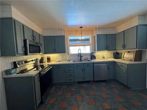 a kitchen with granite countertop a sink dishwasher stove and cabinets