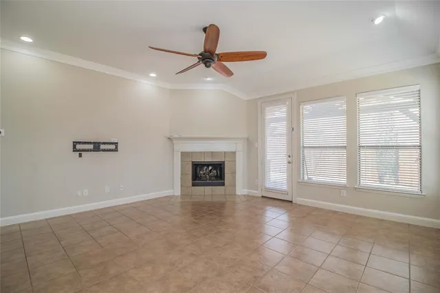 a view of an empty room with chandelier fan and fire place