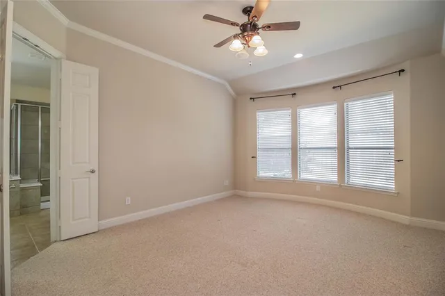 an empty room with chandelier fan and windows