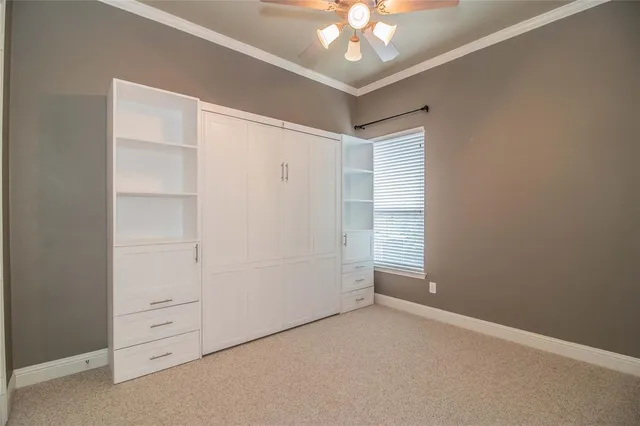 an empty room with a chandelier fan and closet