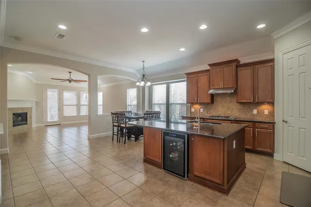 a kitchen with stainless steel appliances granite countertop a stove top oven a sink dishwasher a dining table and chairs with wooden floor