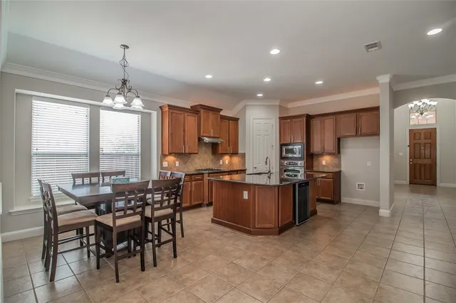 a kitchen with stainless steel appliances granite countertop a stove top oven a sink dishwasher a dining table and chairs with wooden floor